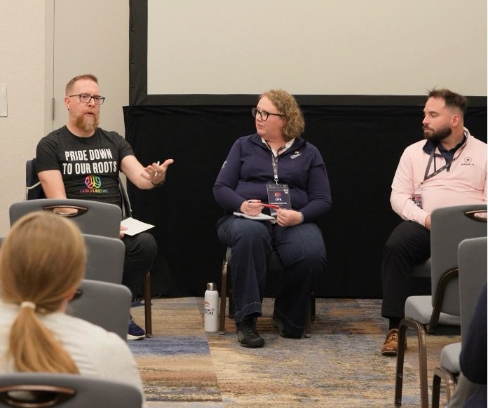 Andrew, in a Pride Down to Our Roots t-shirt, speaking on a panel at the Open Fields Alliance conference